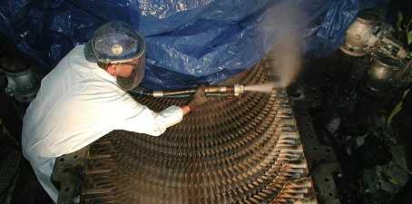 Dry ice blasting—technician using protective gear and a blasting tool to clean industrial equipment surfaces.