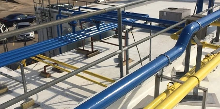Industrial pipes painted in bright blue and yellow for OSHA safety color coding, running across a facility rooftop.