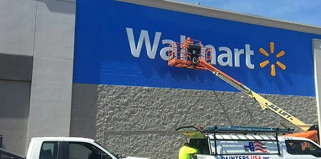 Commercial exterior painting—workers on a lift painting a Walmart store facade in blue.