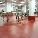 Restaurant or food facility interior with bright red epoxy flooring and freshly painted white columns around stainless steel equipment.