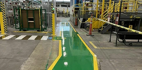 Warehouse floor markings and line striping—bright green walkway and yellow safety lines painted in an industrial facility.